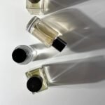 Alt Text: A minimalistic arrangement of four elegant perfume bottles casting soft shadows on a white background, symbolizing the journey to discovering a signature scent.