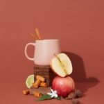 A curated arrangement featuring an apple, cinnamon sticks, caramel, and other natural elements on a warm background, symbolizing fragrance families.