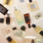 A soft-focus arrangement of various perfume bottles from different brands, showcasing the diversity of fragrances and their elegant packaging