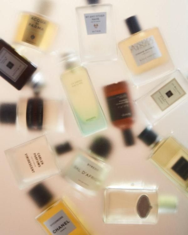 A soft-focus arrangement of various perfume bottles from different brands, showcasing the diversity of fragrances and their elegant packaging