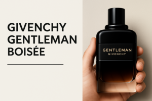 A hand holding a bottle of Givenchy Gentleman Boisée Eau de Parfum against a neutral background, with bold typography displaying the fragrance name.