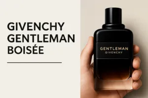 A hand holding a bottle of Givenchy Gentleman Boisée Eau de Parfum against a neutral background, with bold typography displaying the fragrance name.