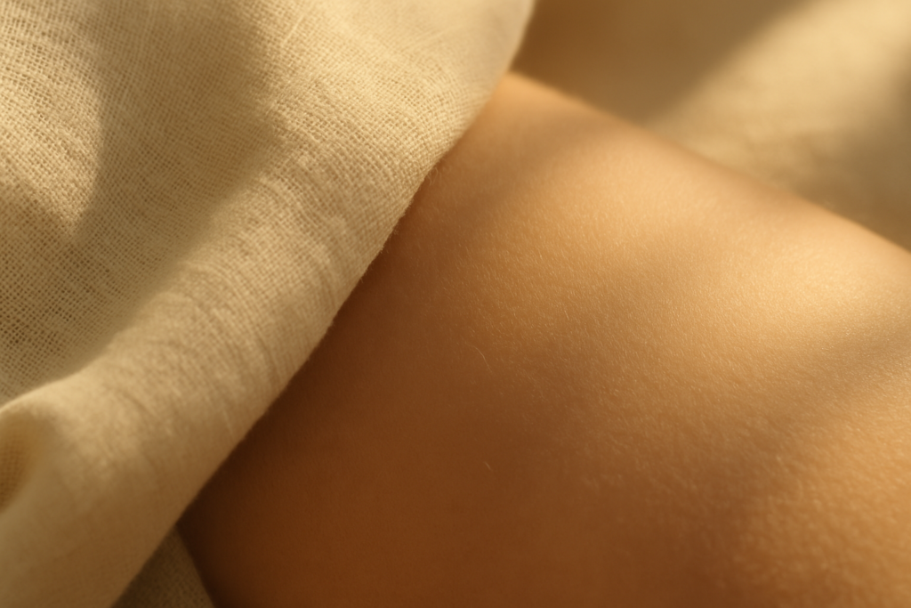 Soft golden light illuminating smooth fabric and skin texture representing the scent of Iso E Super in perfumery