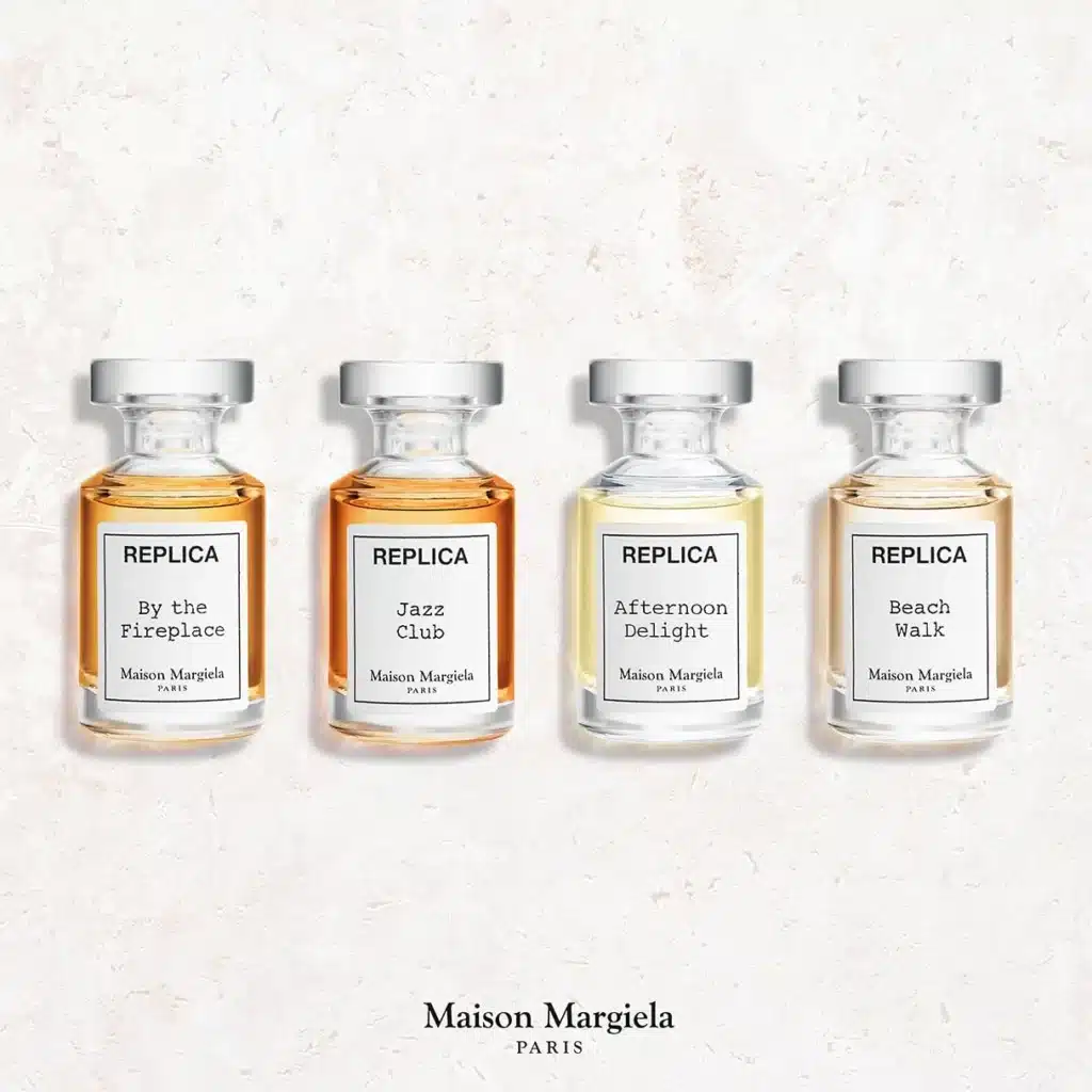 Four Maison Margiela Replica perfume bottles By the Fireplace, Jazz Club, Afternoon Delight and Beach Walk lined up on a light background